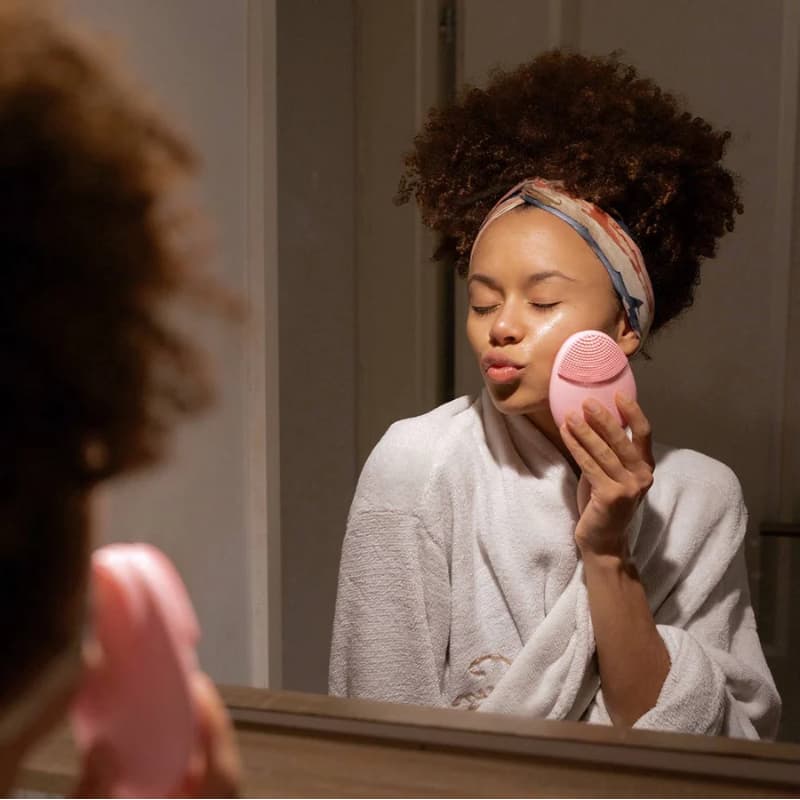 Femme dans sa routine beauté avec brosse PureGlow rose Cypaura