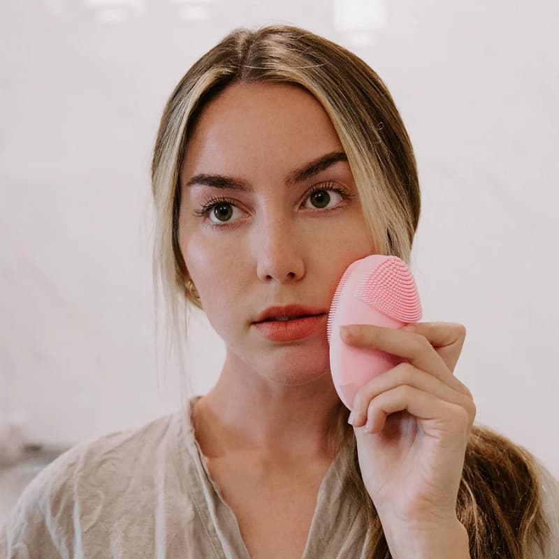 Femme souriante satisfaite après nettoyage avec brosse PureGlow rose