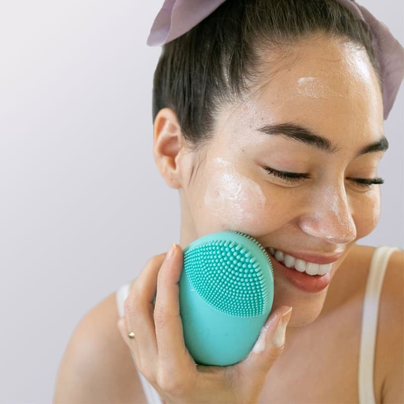 Femme asiatique utilisant brosse PureGlow bleue - produit universel